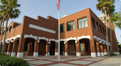 Image of 2 story red brick Tavares City Hall building with the American flag in the foreground